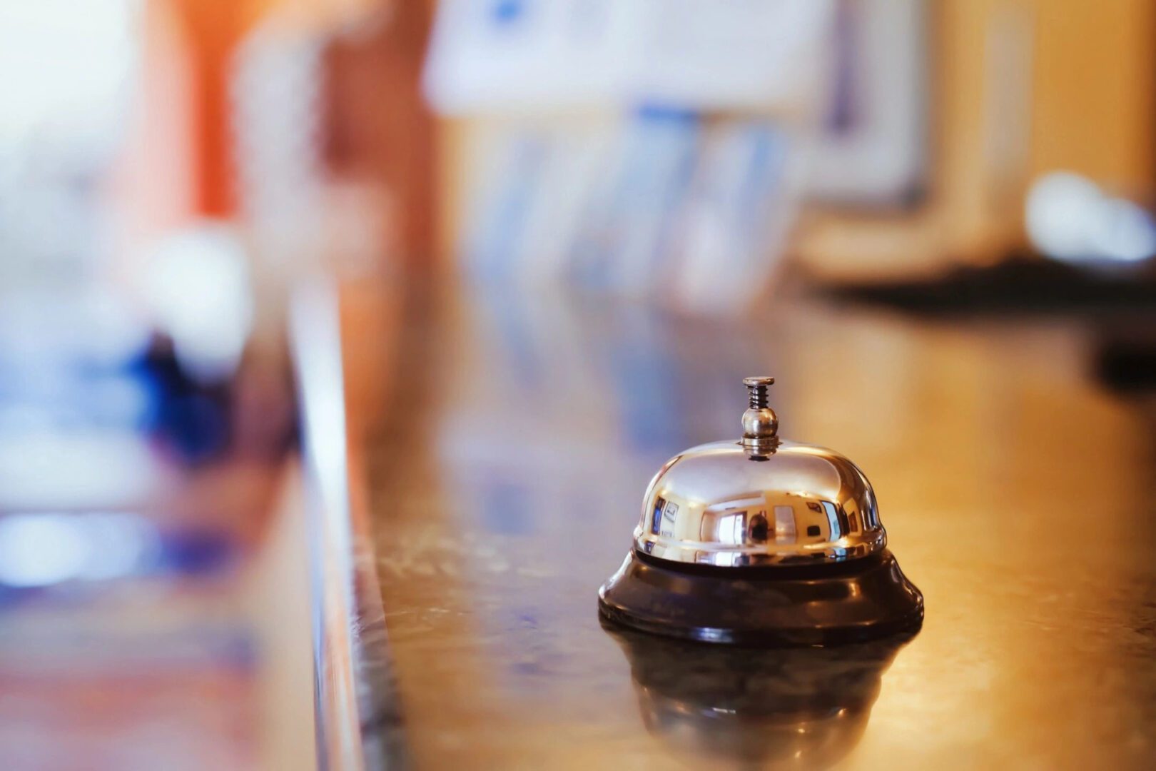 A shiny service bell on a polished wooden counter at a reception desk.