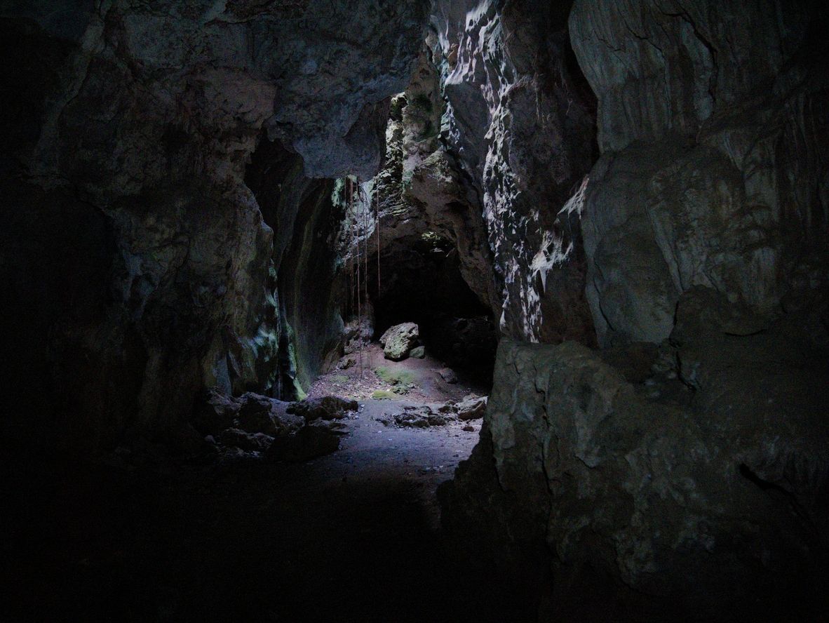 Dimly lit rocky cave interior with a narrow passage.