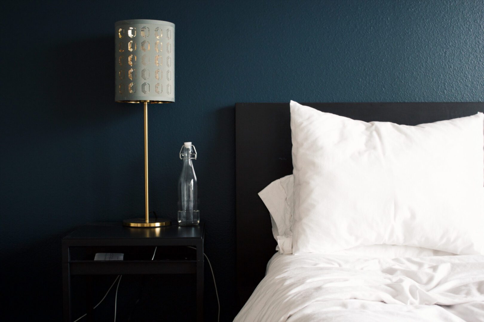 Modern bedroom corner with a textured lamp and clear glass sculpture.