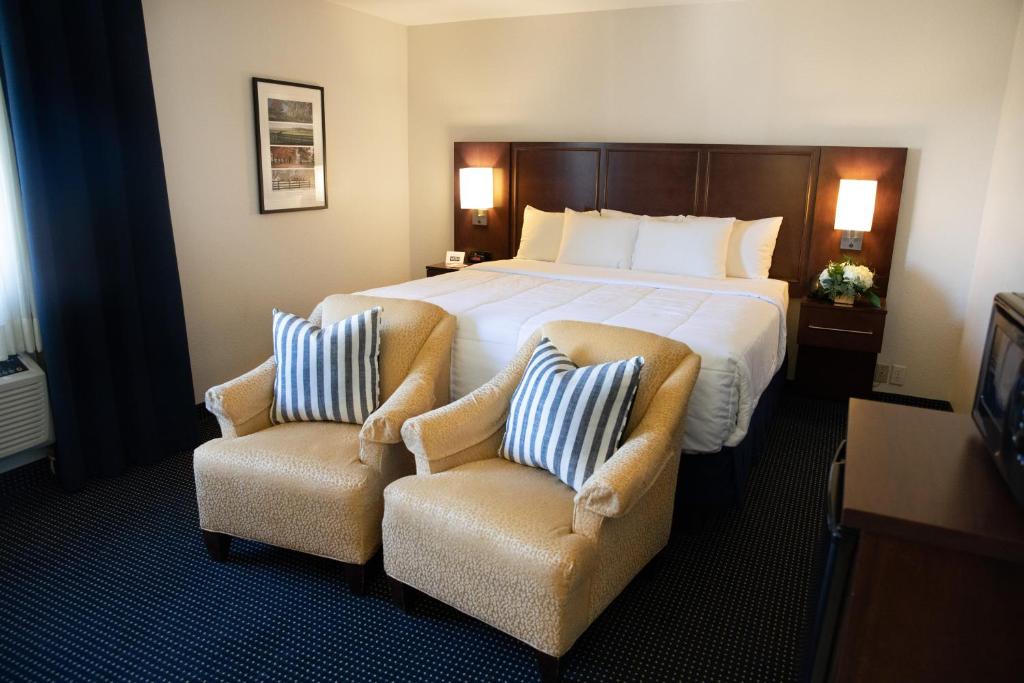 Cozy hotel room with a comfortable bed and two beige armchairs.